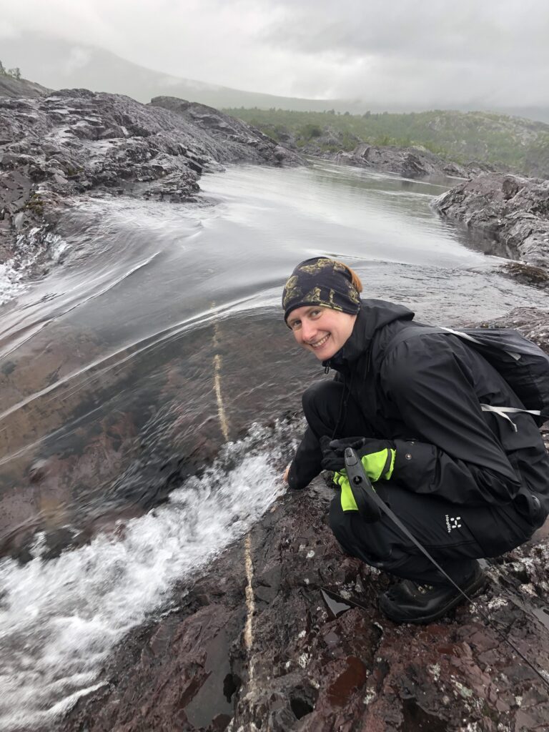 Tim sitting smiling by a waterfall